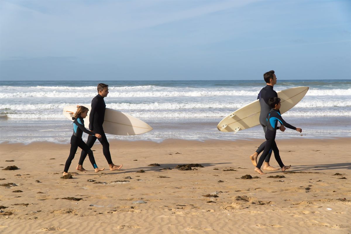 Family with surfboards on the beach in Taghazout — family surf holiday guide
