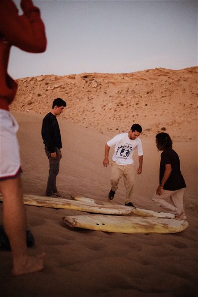 Sandboarding down a golden dune near Taghazout, Morocco