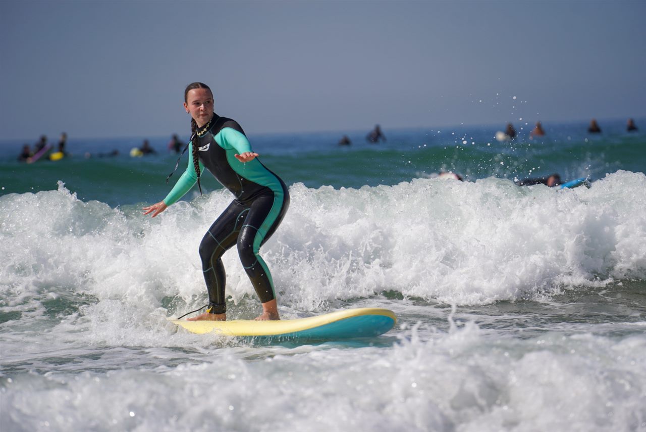 Beginner surfer riding a wave during a group surf lesson in Taghazout, Morocco